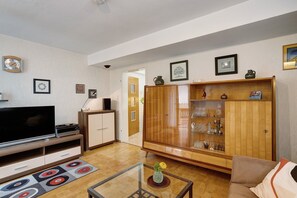 Un salon équipé d’un téléviseur à écran plat, d’un meuble en bois et d’une table basse en verre.