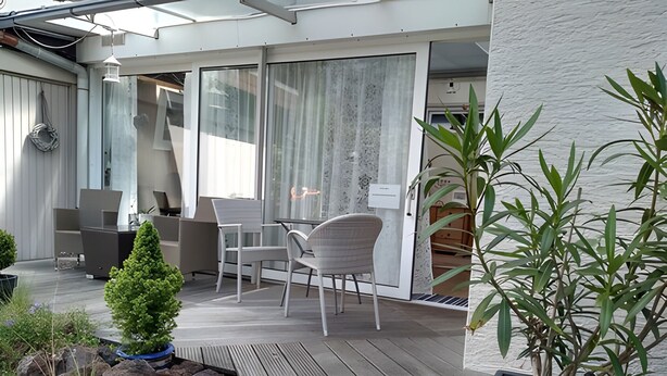 Un patio moderno al aire libre con terraza de madera, zona de estar y macetas.