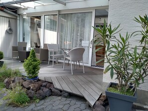 Une terrasse extérieure moderne, dotée d’une plateforme en bois, d’un espace salon et de plantes en pot.
