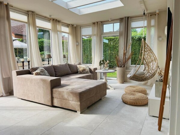 A modern living room with a sectional sofa, a hanging chair, and a round table.