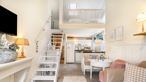 A spacious living area with a staircase, a kitchen, and a dining area. - Studio Malibu S by the Lake (Wettringen)