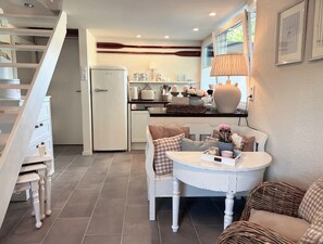 Cocina compacta con refrigerador, estufa y comedor con mesa y sillas.
