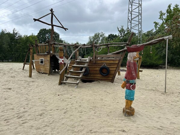 Een houten piratenschip speeltoestel met een ladder en een poppetje.