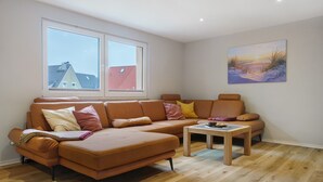 A modern living room with a sectional sofa, a small coffee table, and a painting on the wall.
