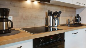 A modern kitchen with a built-in stove, a coffee maker, and a knife block.