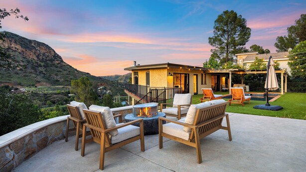 A patio with outdoor furniture and a fire pit, overlooking a mountainous landscape. - Private Pool | 2 Firepits | Peloton | Mtn Views | The Lake House at Malibu (Agoura Hills)