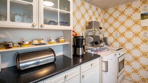 Una cocina con armarios blancos, un tostador, una cafetera y un refrigerador.