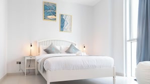 Un dormitorio moderno con una cama blanca, mesitas de noche y una obra de arte en la pared.