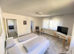 A hotel room with a bed, a TV, a small table, and a chair. - Apartment 'Belchen' with Balcony and Wi-Fi (Bad Krozingen)