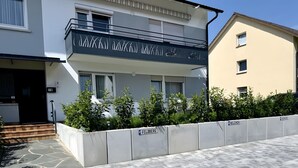 A residential building with a balcony, a paved driveway, and a low wall with a parking sign. - Apartment 'Belchen' with Balcony and Wi-Fi (Bad Krozingen)