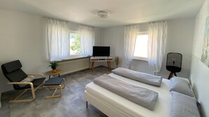 A room with a bed, a desk, a chair, a television, and windows with curtains. - Apartment 'Belchen' with Balcony and Wi-Fi (Bad Krozingen)