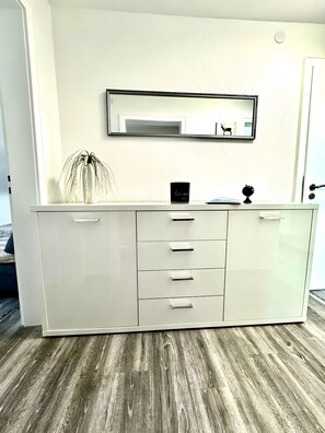 Un meuble blanc avec des tiroirs et un miroir au-dessus.