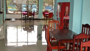 En restaurang med ett välpolerat golv, bord och stolar i trä samt en försäljningsautomat för Coca-Cola.