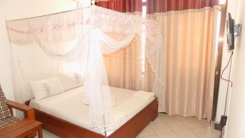 Una cama con dosel, una mesita de noche y cortinas.