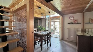 A wooden interior with a dining area, a kitchen, and a view through a glass door.