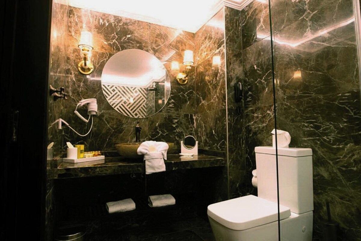 A modern bathroom with a marble vanity, a round mirror, and a toilet.