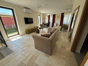 A spacious living room with a sofa set, a television, and a dining area. - Eco Therma Village Spa & Sport (Balchik)