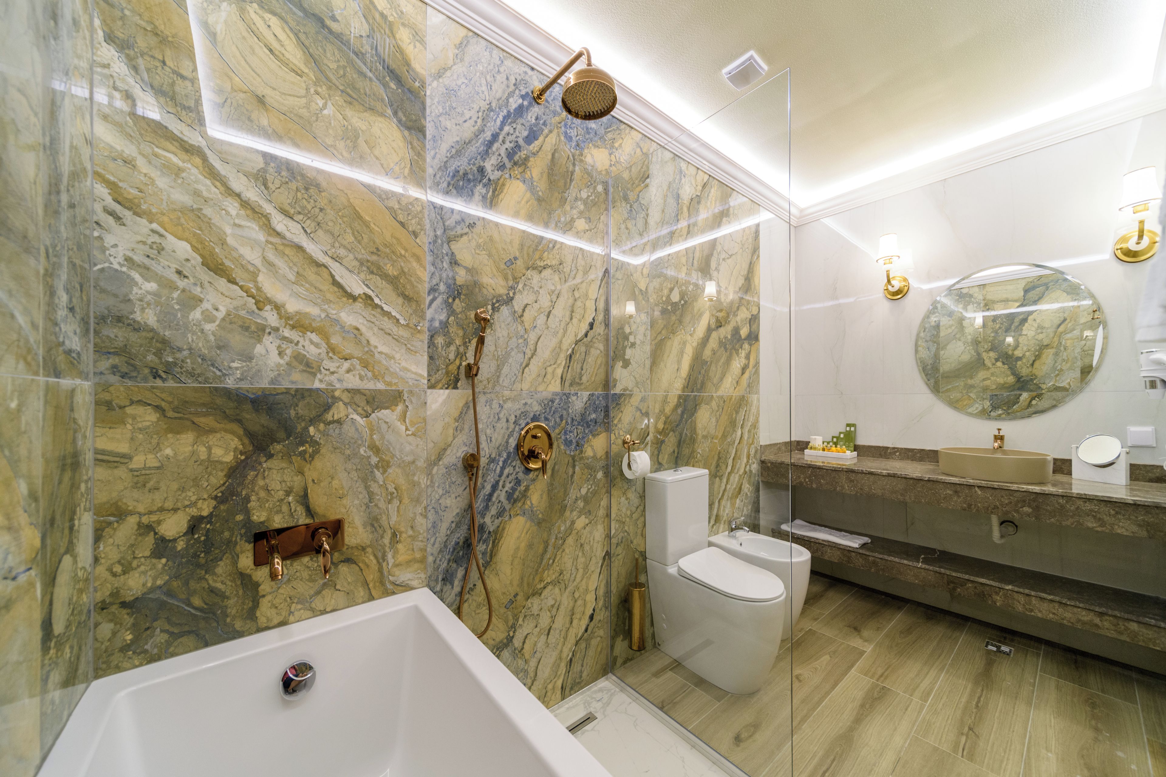 Une salle de bain moderne avec un mur en marbre, une baignoire sur pieds, des toilettes et un meuble-lavabo avec un miroir.