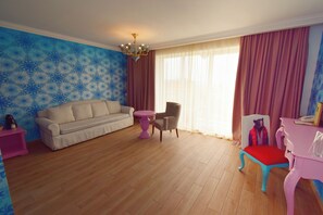 A living room with a beige sofa, a pink table, a chair, and a small table with a teddy bear. - Eco Therma Village Spa & Sport (Balchik)