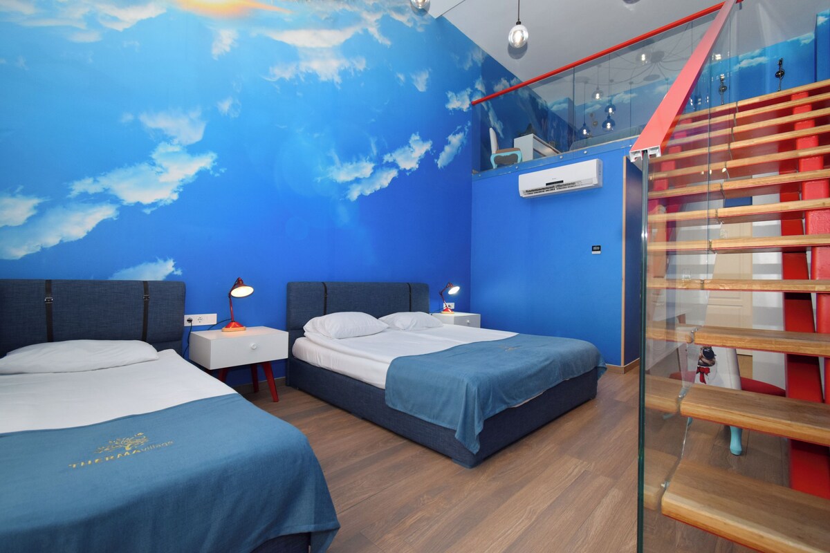 A hotel room with two beds, a glass staircase, and a view of the sky through the ceiling.