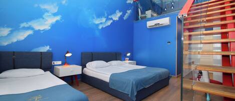 Quarto de hotel com duas camas, escada de vidro e vista do céu pelo teto.