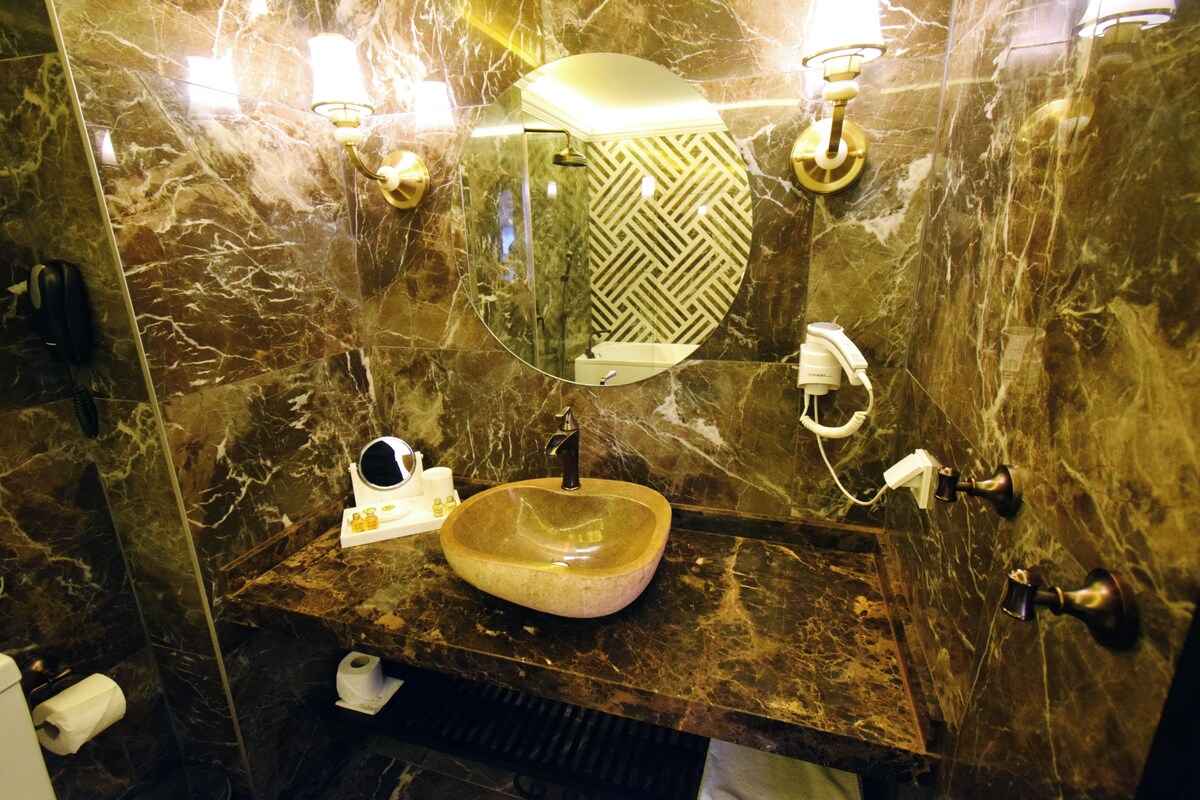 A bathroom with a marble wall, a round sink, and a mirror.