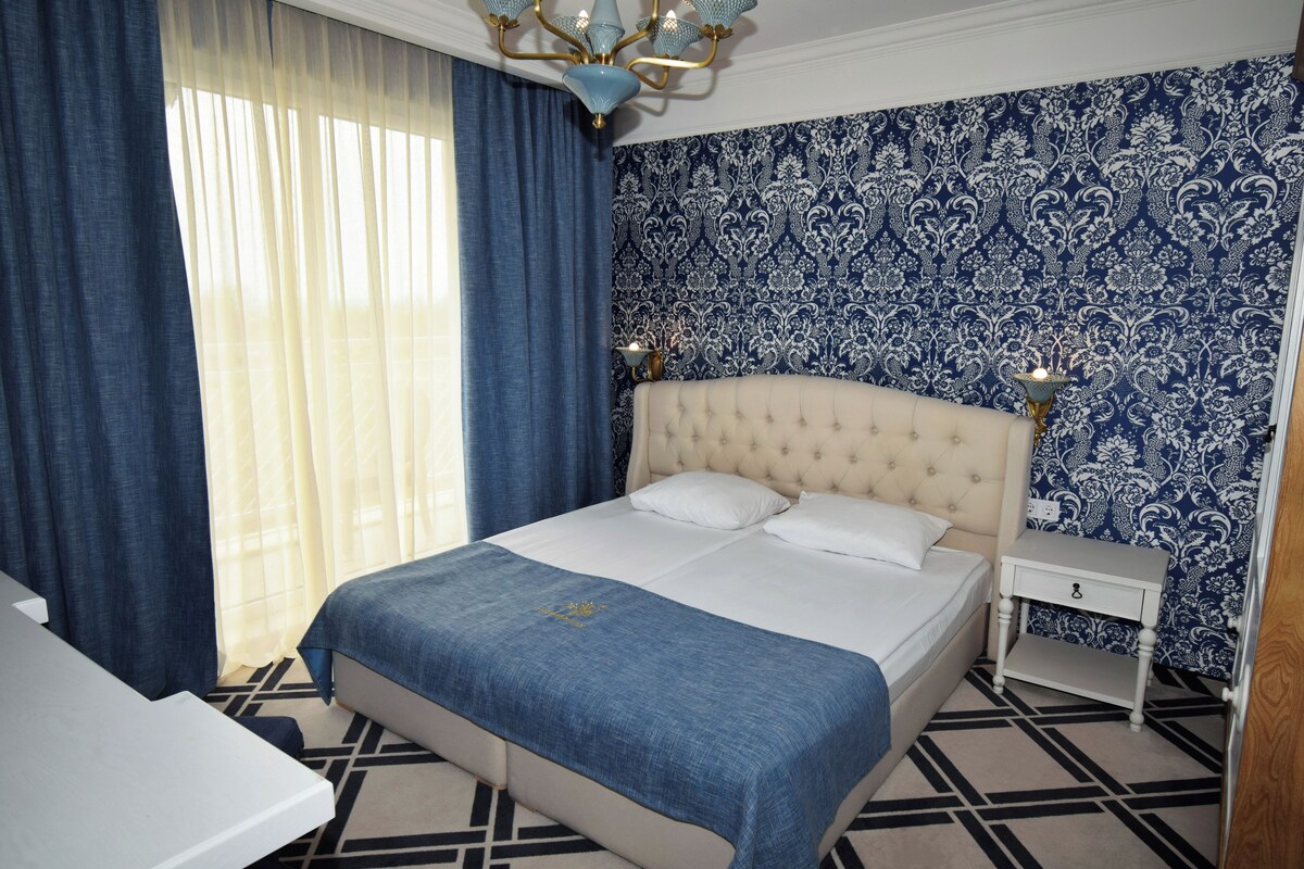A hotel room with a large bed, a bedside table, and a nightstand.