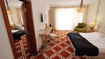 A hotel room with a bed, a desk, a chair, a mirror, and a window with curtains.