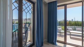 Une pièce dotée d’une porte-fenêtre coulissante donnant sur une terrasse extérieure avec une piscine et du mobilier.