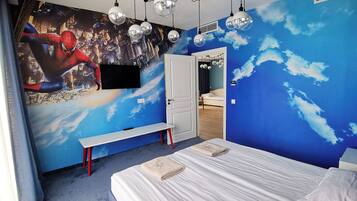 Un dormitorio con un mural de un paisaje urbano y nubes, una cama, un banco y un armario.