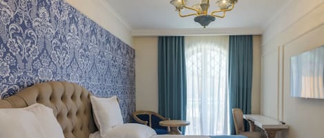 A hotel room with two beds, a chandelier, a desk, and a chair.