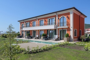 A two-story building with a swimming pool, outdoor seating, and a garden. - Eco Therma Village Spa & Sport (Balchik)