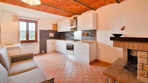 A modern kitchen with white cabinets, a built-in oven, and a brick fireplace.