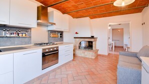 A modern kitchen with white cabinets, a gas stove, and a stone fireplace.