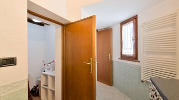 Ein Badezimmer mit Holztür, Heizkörper und einem fenster mit Vorhang.