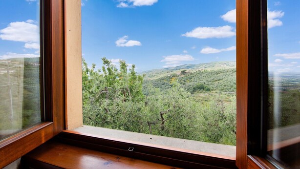 A window with a view of a green landscape and a clear blue sky.