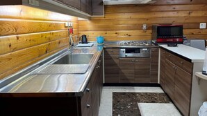 A compact kitchen with wooden walls, stainless steel appliances, and a small countertop. - SHODOSHIMA PRIVATE CAMP SITE (Shodoshima)