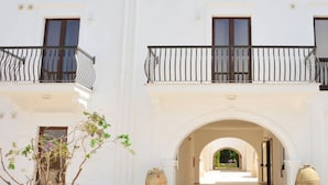 A white building with balconies, an archway entrance, and a garden view. - Mare Nostrum Hotel (Fasano)