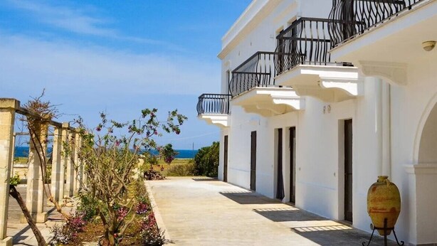 A white building with balconies, a courtyard, and a view of the sea. - Mare Nostrum Hotel (Fasano)
