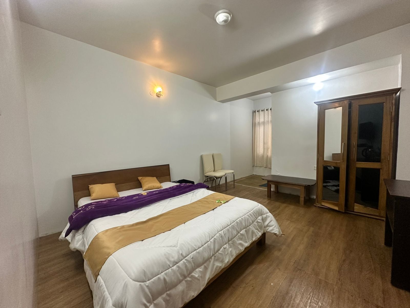 Un dormitorio con cama, una silla, un escritorio y un armario.
