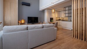 Una sala de estar moderna con un sofá seccional gris, un televisor de pantalla plana y un comedor con una mesa y sillas de madera.