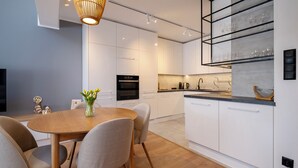Una cocina moderna con armarios blancos, una mesa de comedor de madera y un florero con flores.