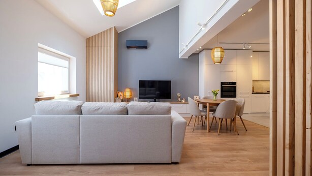 Una sala de estar moderna con sofá, televisor y comedor.
