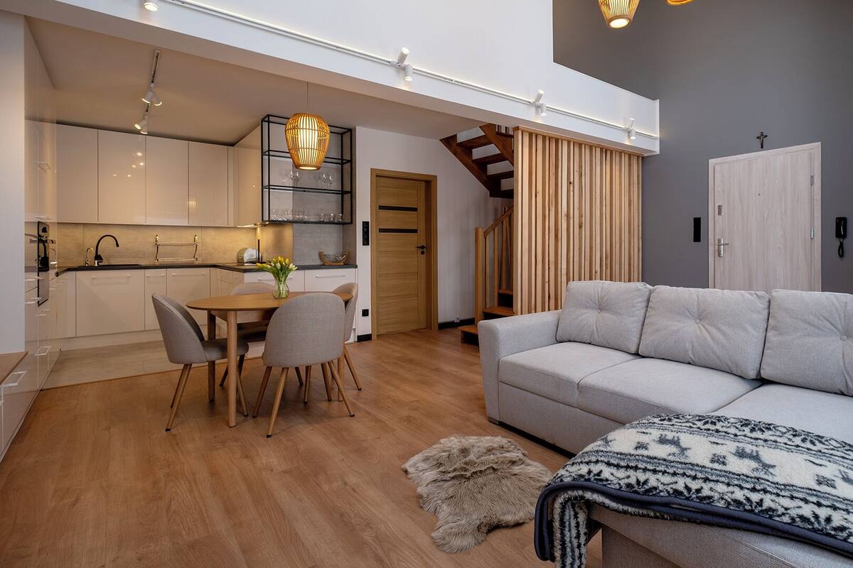 A modern apartment with a dining area, kitchen, and living room.