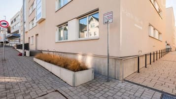 Ein Gebäude mit flacher Fassade, großen Fenstern und einem schmalen Bürgersteig.
