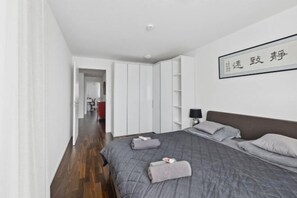 A bedroom with a bed, a wardrobe, and a wall-mounted shelf.