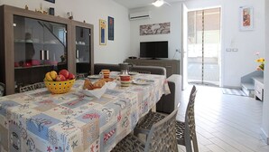 A dining area with a table set for two, a television, and a view of the outside. - Stunning  villa for 6 people with A/C, WIFI, TV, terrace and pets allowed (Lido Degli Estensi)