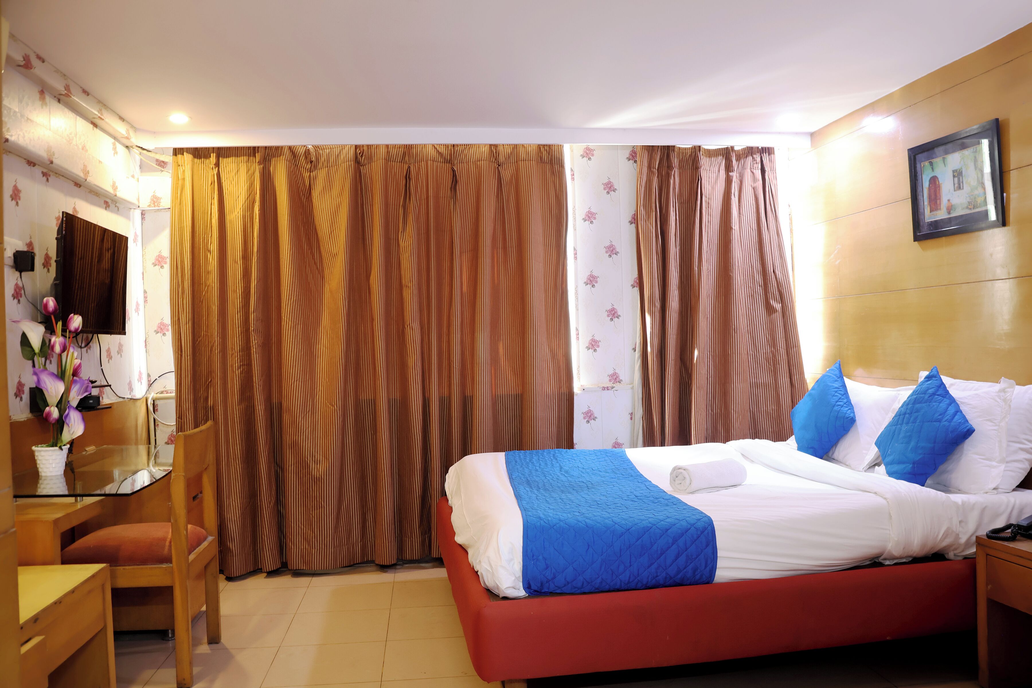 Une chambre d’hôtel avec un lit, un bureau, une chaise et des rideaux.