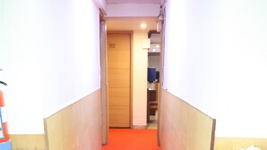 A narrow hallway with red carpet, wooden cabinets, and a door marked 102. - HOTELS DAFFODILS (New Delhi)