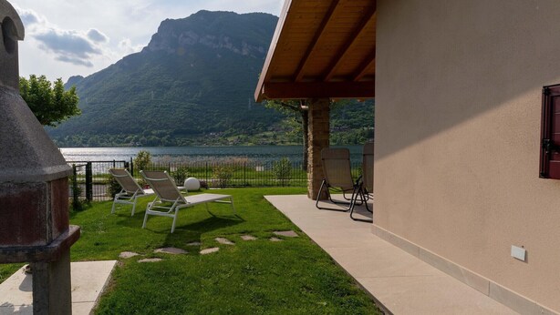 A patio with lounge chairs overlooking a lake and mountains. - Villa by Lake Idro with Mountain Views (Idro (bs))